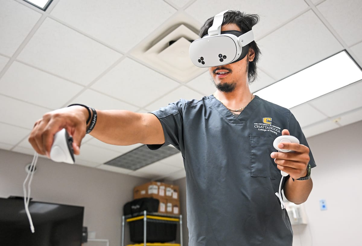 A UTC nursing student uses hand controllers while wearing a virtual reality headset during a clinical simulation exercise.