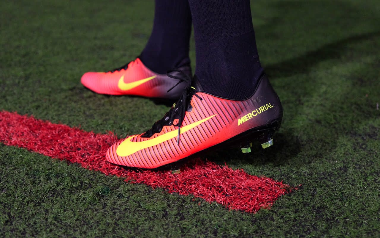  A close-up of a pair of red and yellow soccer cleats on a green field with a red line, representing the search query 'Nostalgia in soccer cleats'.