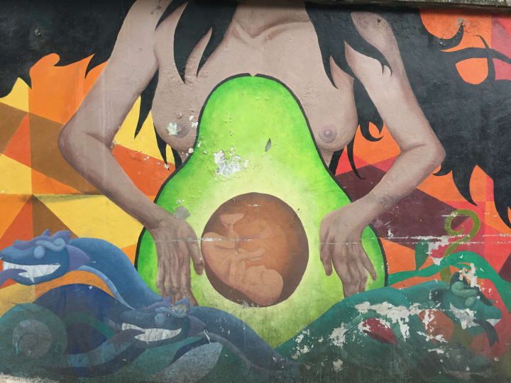 street art graffiti of a pregnant woman with avocado belly