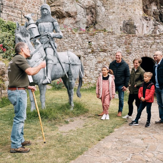 Mont Orgueil Castle group listen to talk from volunteer by statue