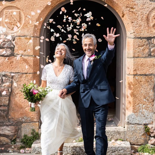 Man and Woman getting married walk through arch with confetti