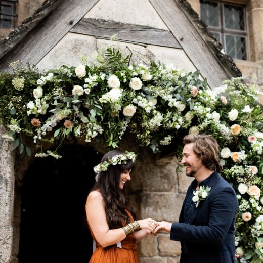 Hamptonne Man and Woman outside building with flower arch