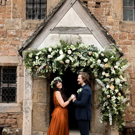 Hamptonne Man and Woman outside building with flower arch