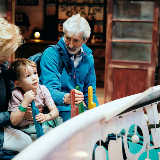 Maritime Museum child plays with globe exhibit with grandparents