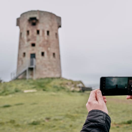 Person takes photo of a round stone tower