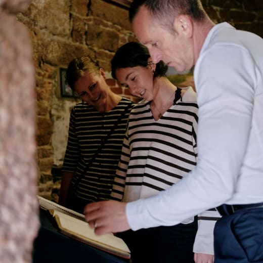 Three people read a book inside a stone building