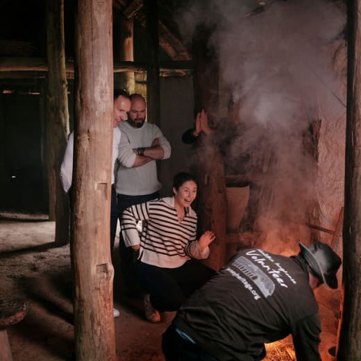 People clap and cheer as volunteer makes fire