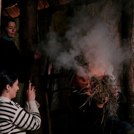 Girl takes picture of a fire starting in a small straw bale