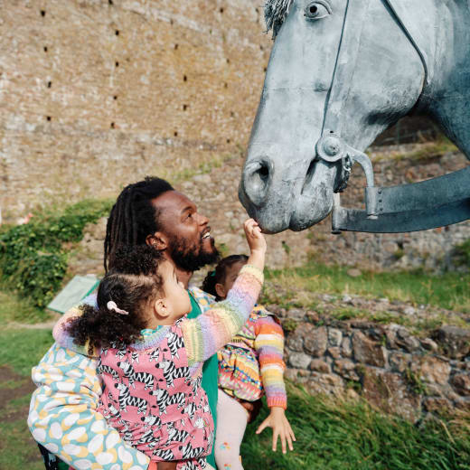 Young girl, held by father touches an exhibit