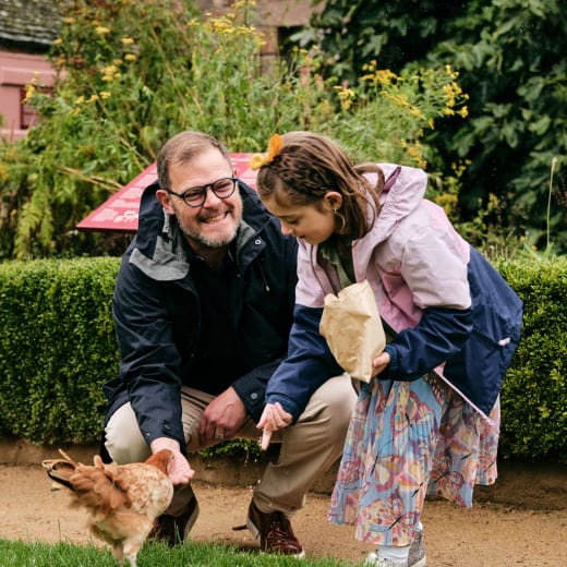 Father and daughter feed a chicken