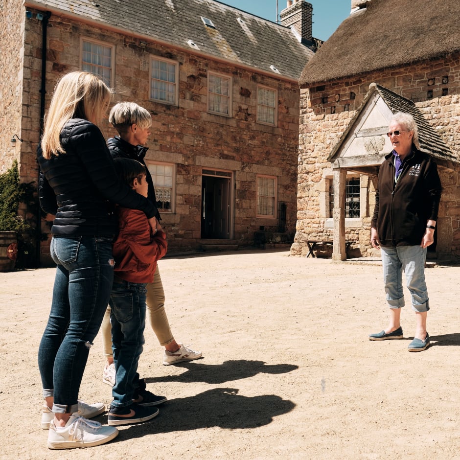Hamptonne Couple listen to guide in courtyard