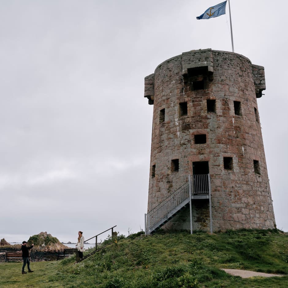 Couple take photo of large round tower with a flag flying