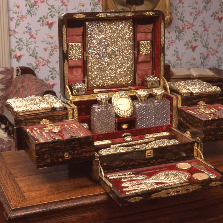 An ornate gold travelling case with mirrors, combs and other personal items