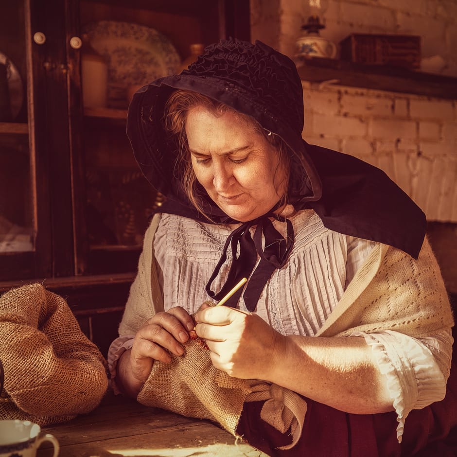 Woman in a shall knits at a table.