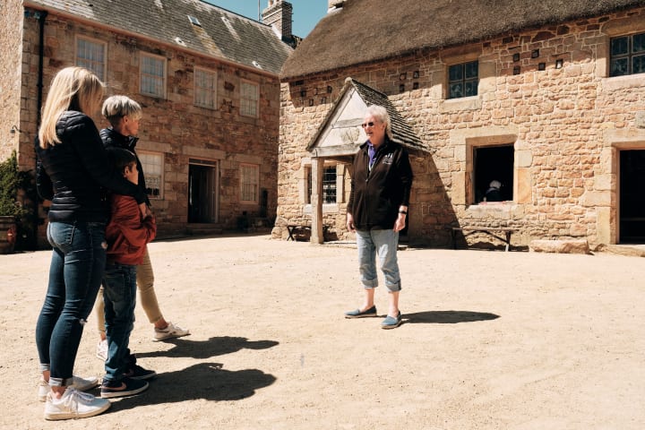 Hamptonne Couple listen to guide in courtyard