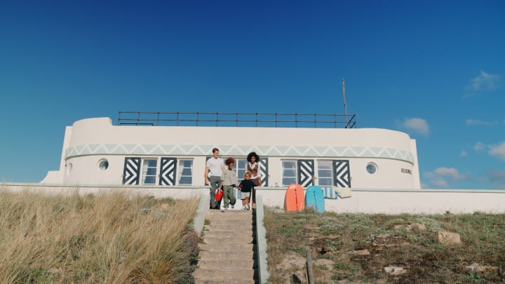 Family with surf boards sit at the top of some steps