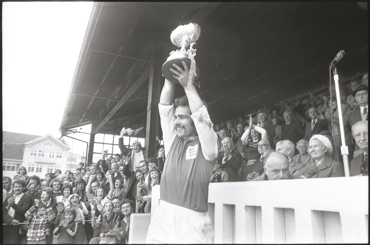 footballer holds trophy aloft.