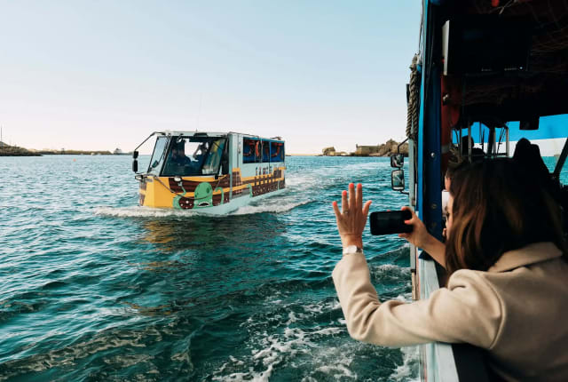 Elizabeth Castle person leans out of ferry to wave at passing ferry