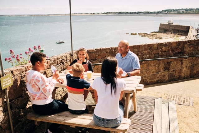 Family of four site on a picnic bench with a view over the harbour