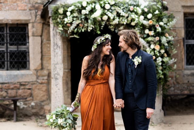 Hamptonne Man and Woman outside building with flower arch