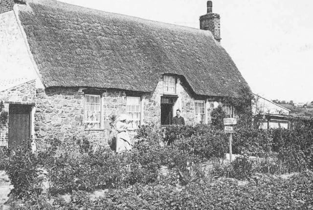 Black and white photo of a thatched cottage