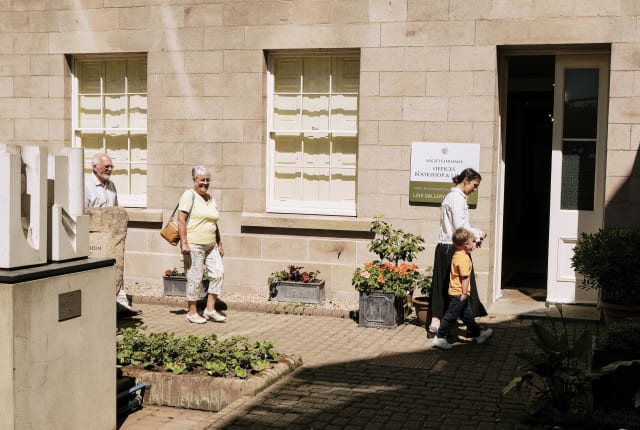 Link Gallery family of four walk into open doorway from a courtyard