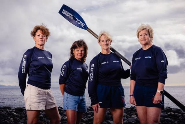 Four women in rowing wear with an oar