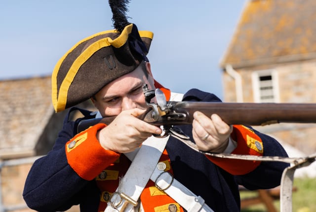 Person in Militia costume aims a gun