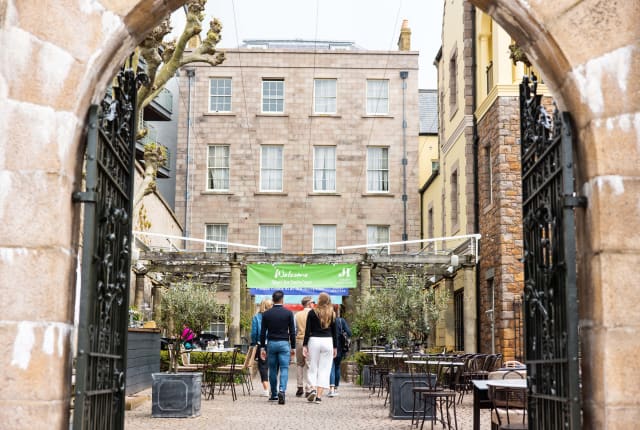 group of people walk towards a building through large gates