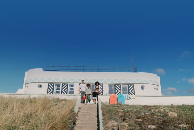 Family with surf boards sit at the top of some steps