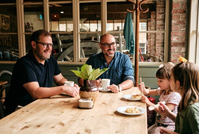 Family sit around large pine table