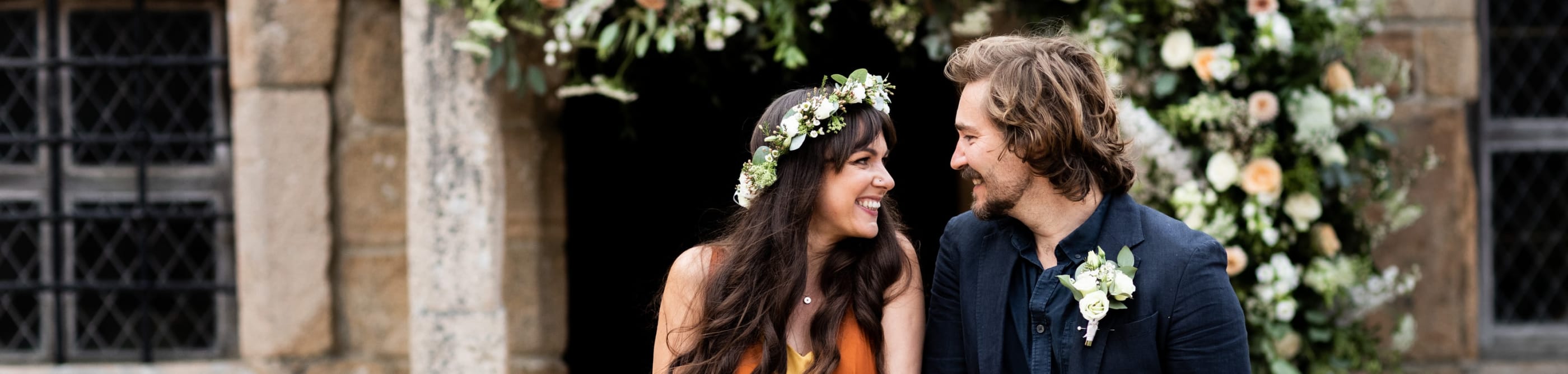 Hamptonne Man and Woman outside building with flower arch