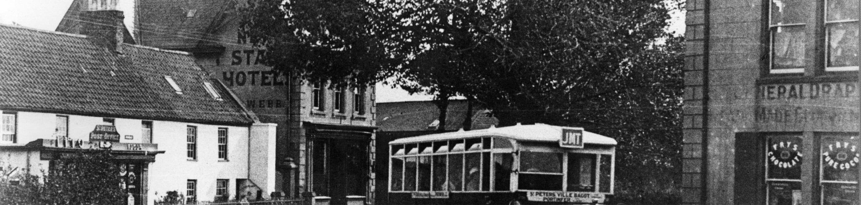 Black and white postcard of St Peter's Village with old bus at bus stop.