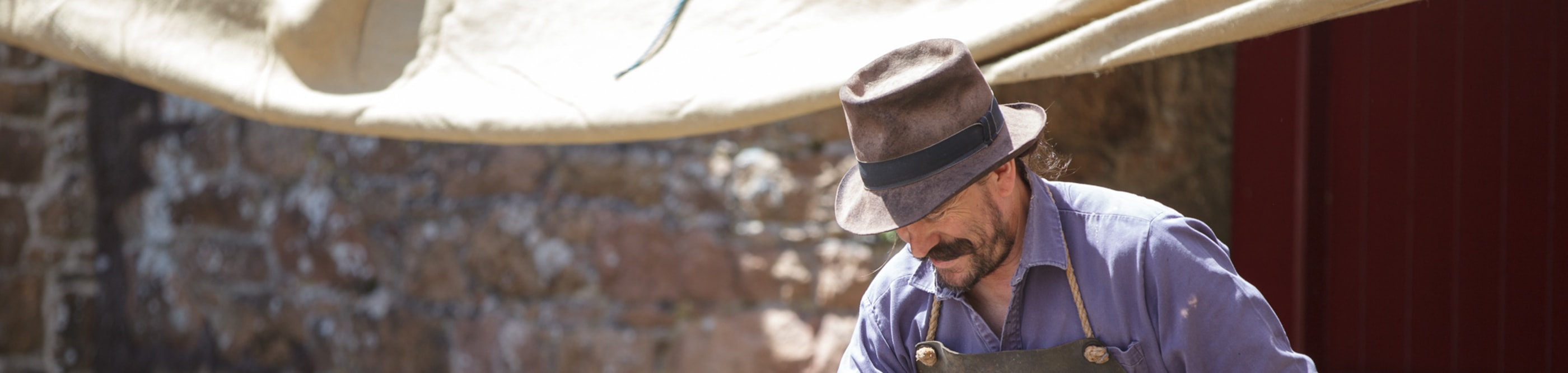 Man in hat works at a forge