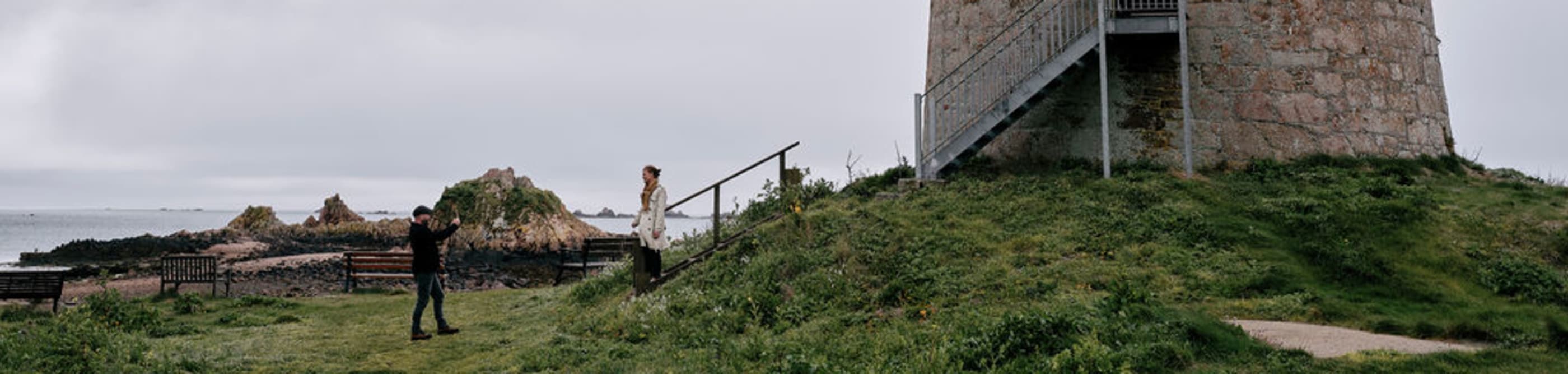 Couple take photo of large round tower with a flag flying