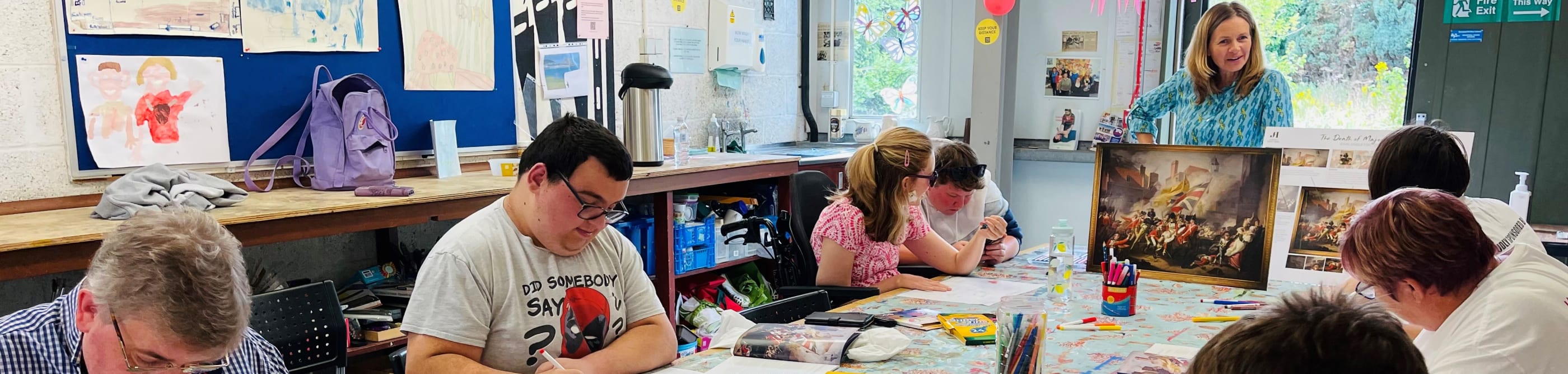 A small group of people sit at a table doing a colouring project