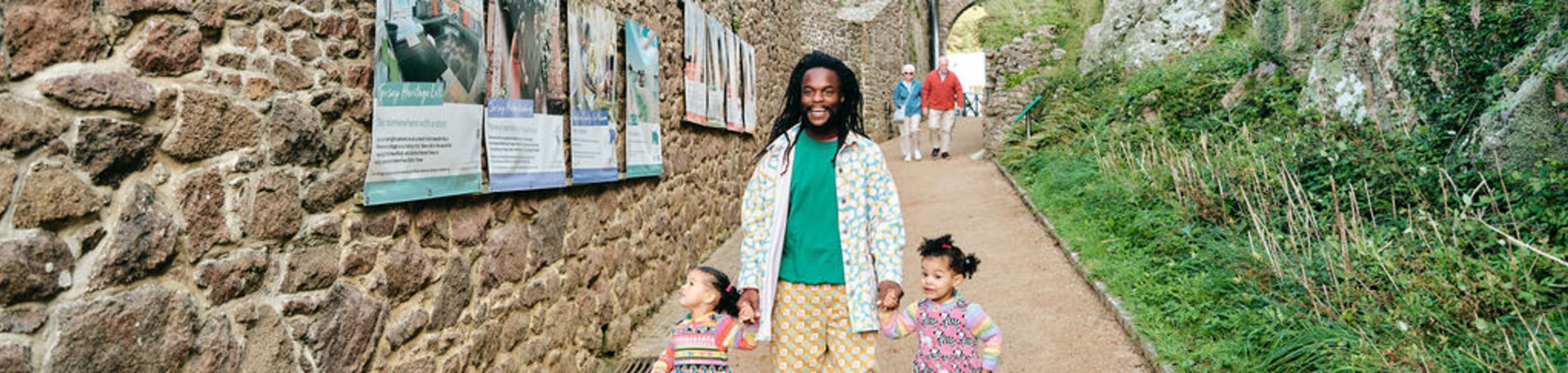 Father and two young daughters walk down a lane