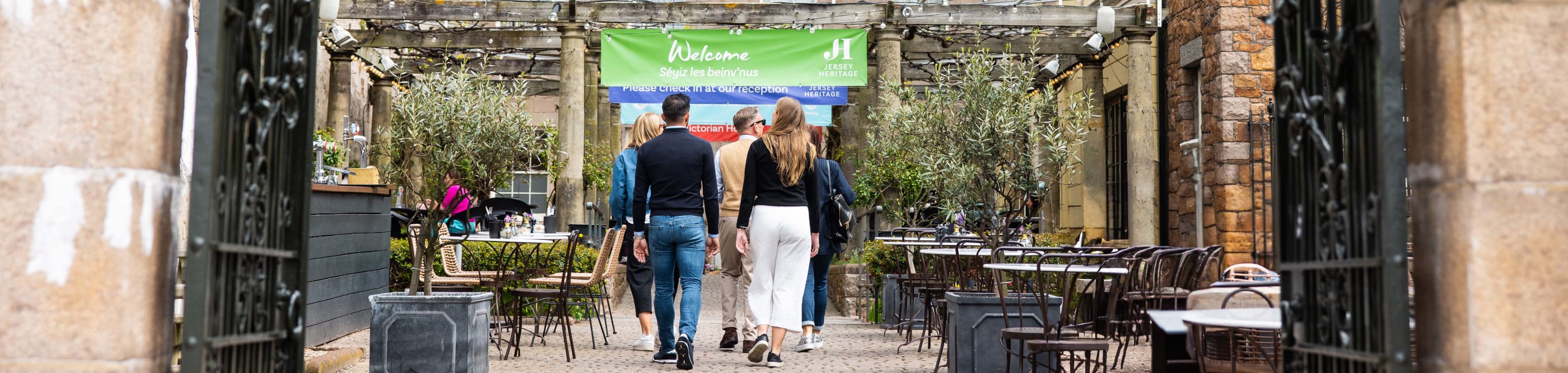 group of people walk towards a building through large gates