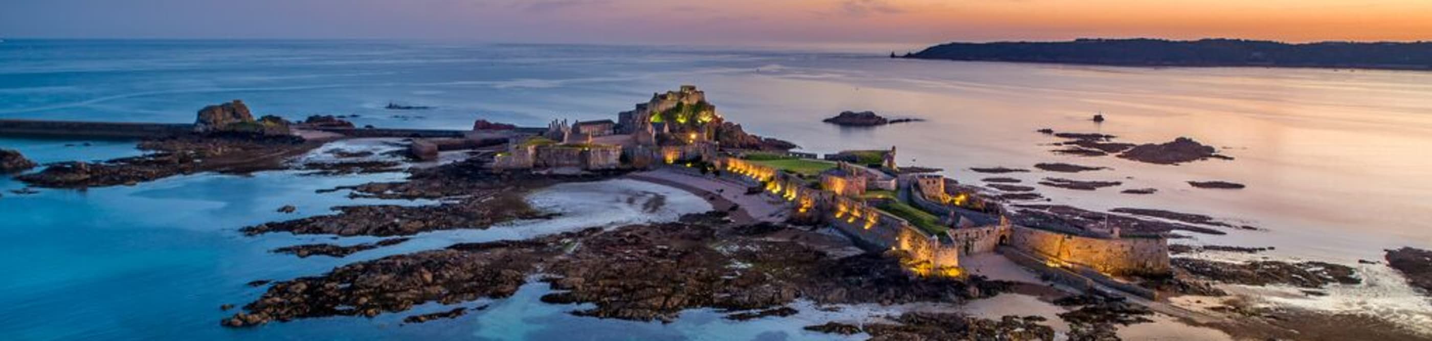 A castle light up at dusk with a red sky