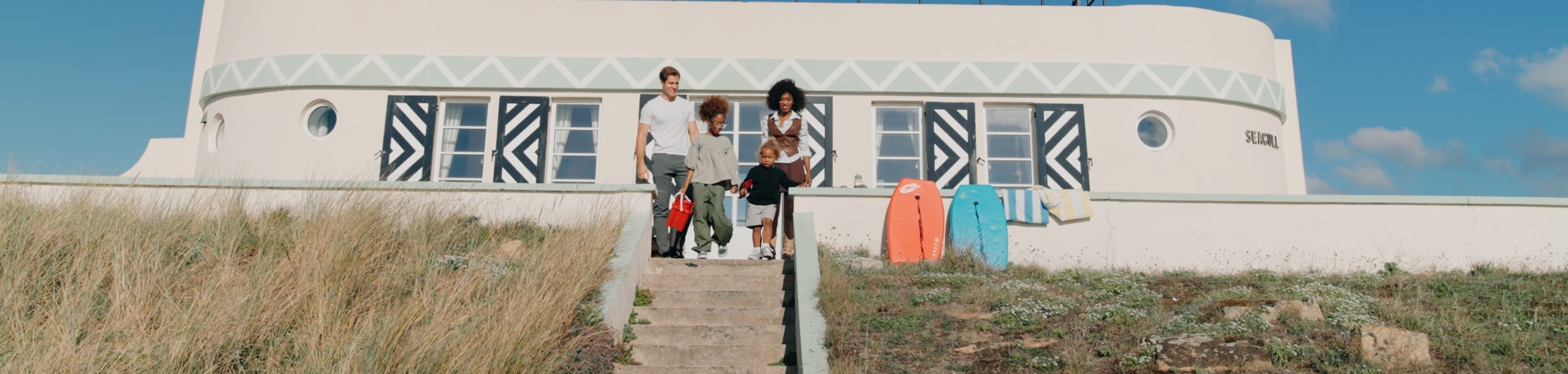 Family with surf boards sit at the top of some steps