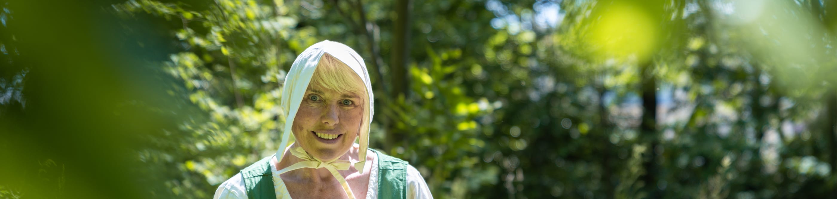 Woman in green costume walks in a field