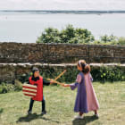 Two children dressed up as knights and princesses play in the garden