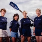 Four women in rowing wear with an oar