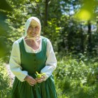 Woman in green costume walks in a field