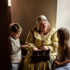A women in costume from 17th century talks to two children