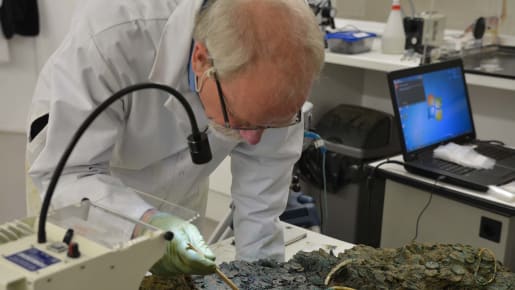 Scientist works on old coins in lab