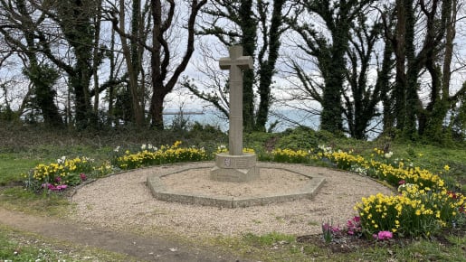 A built stone cross stans in a circle surrounded by plants