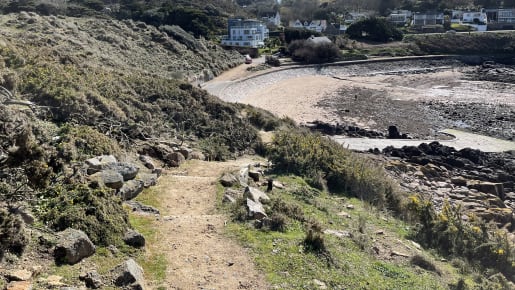 rocky pathway heads down towards a secluded bay