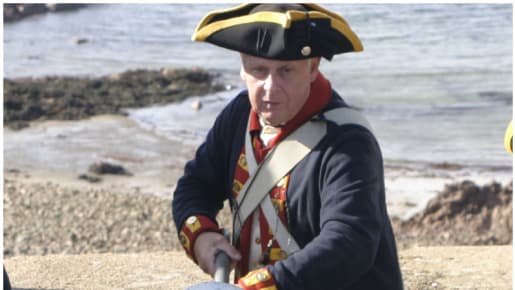 a man in uniform pushes a cannon ball down into a cannon
