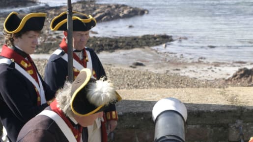 three men in uniform light a touch paper for a cannon